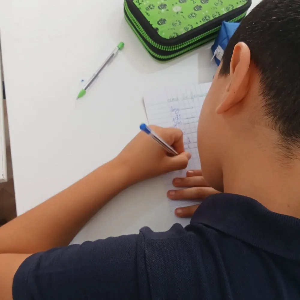 Enfant écrivant sur son cahier pendant un exercice