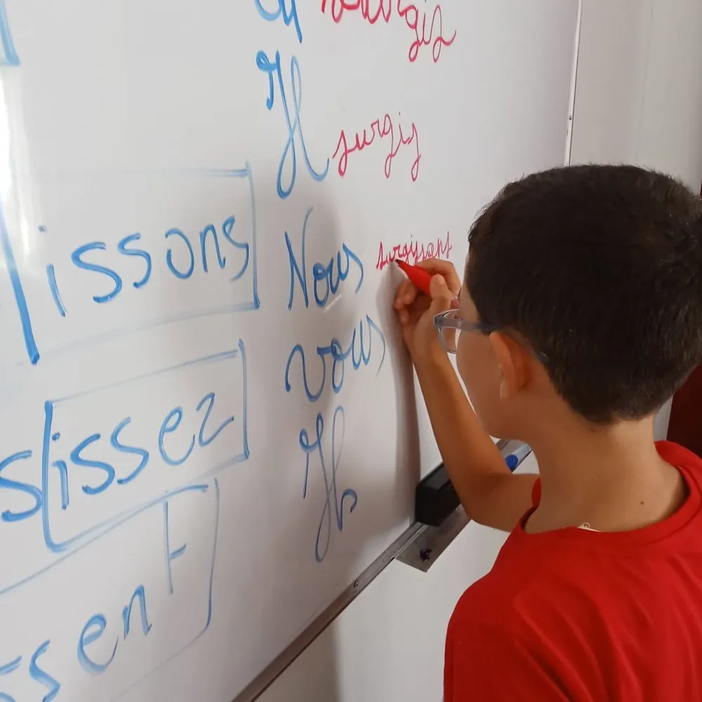 Élève au tableau pendant un atelier de conjugaison française